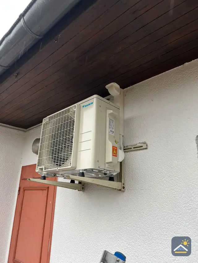 Buitenunit op een muurbeugel onder de dakrand